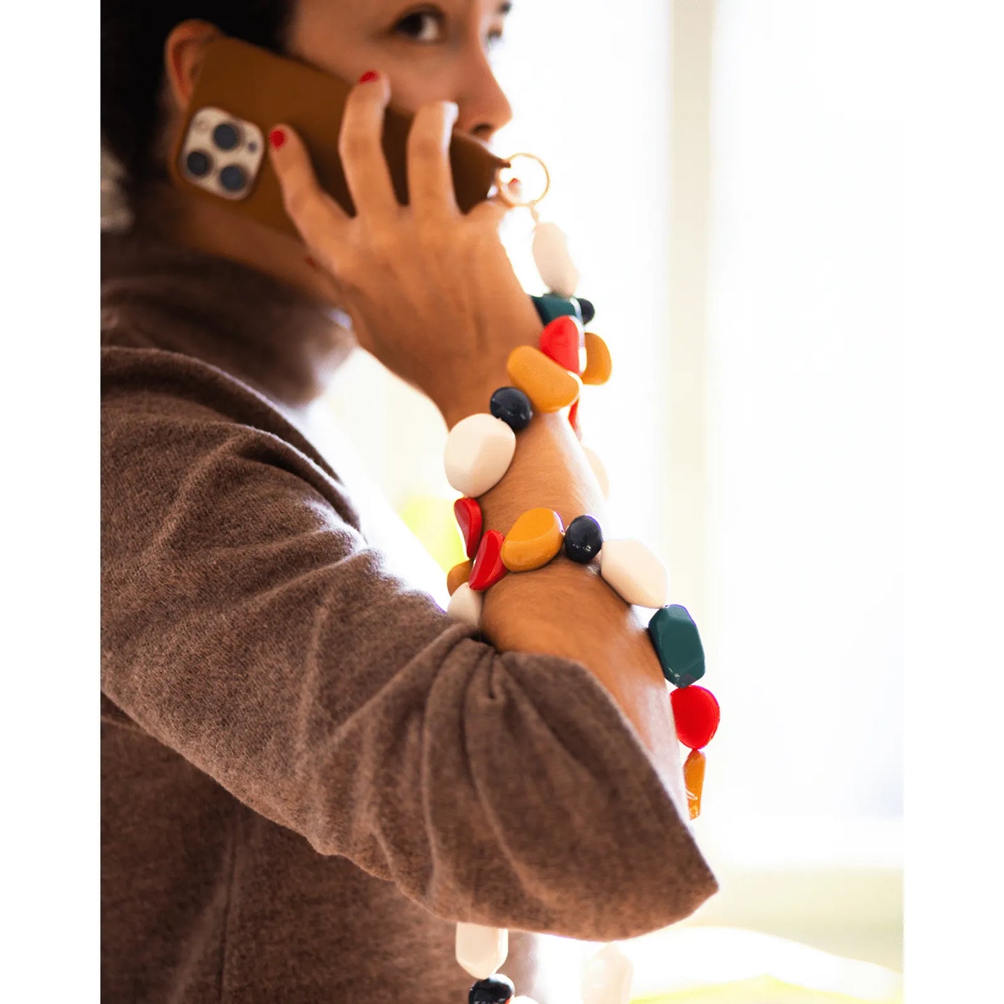 Capinha de celular caramelo com corda de pedras azul, branco e mostarda